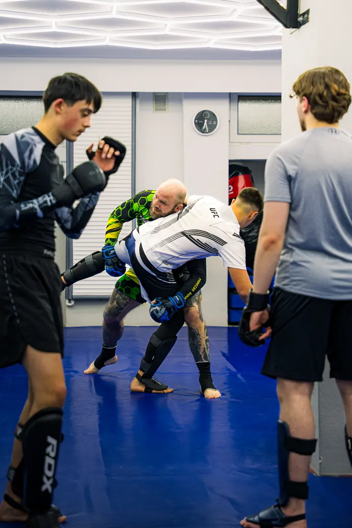 MMA-Training: Trainer und Schüler beim Sparring auf der Matte